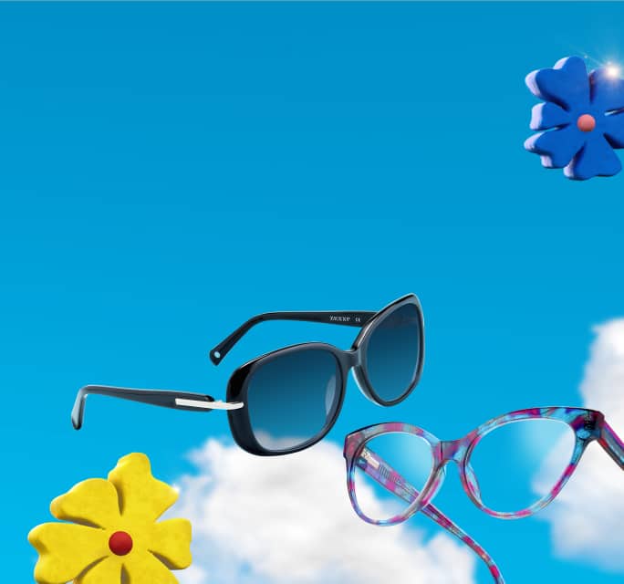 Two pairs of eyewear floating at an angle against a bright blue sky filled with soft white clouds, featuring oversized dark sunglasses with blue gradient lenses and cat-eye optical frames with a colorful patterned print, accompanied by floating blue and yellow toy flowers.