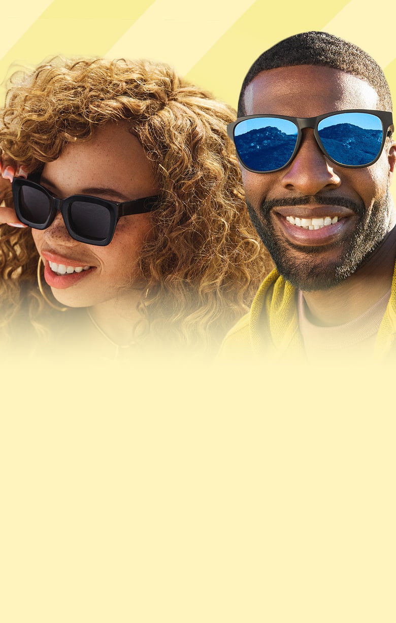 A woman with curly light brown hair wearing black oversized Zenni sunglasses with dark gray lenses and a man with short cropped black hair and a beard wearing black Zenni sunglasses with blue mirror lenses on a yellow striped background.