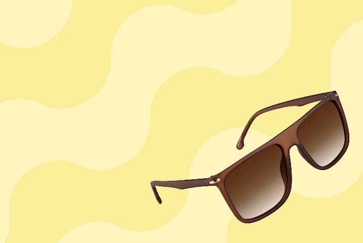 Brown translucent aviator sunglasses with gradient lenses on a yellow wavy background.