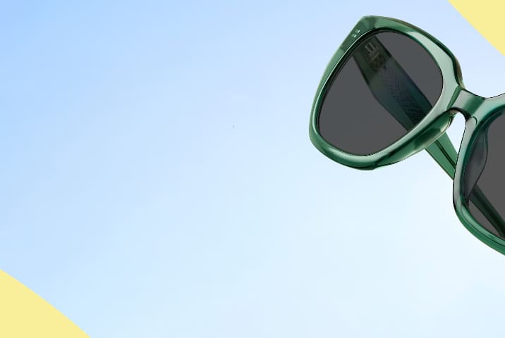 Lentes de Sol Zenni de acetato verde translúcido con lentes gris oscuro. Fondo de rayas azules y amarillas.