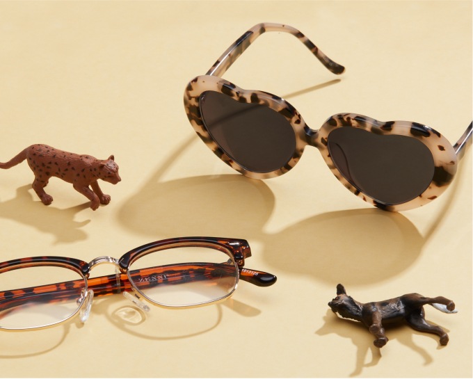 Image of two pairs of zenni glasses against a yellow background, with kids animal toys around them. 