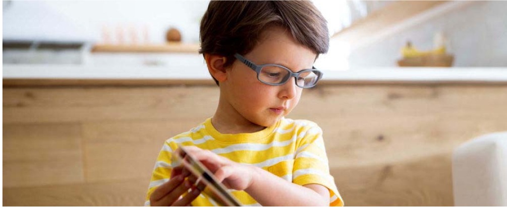 Image of a boy wearing zenni glasses while reading a book. 