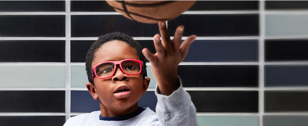 Image of a boy wearing zenni sports goggles while playing basketball. 