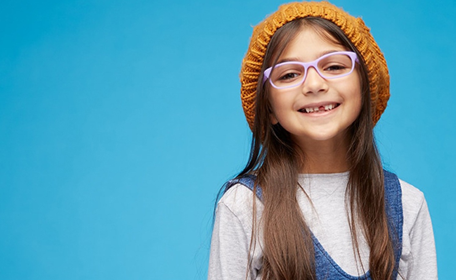 Young girl with long brown hair and slouchy mustard yellow beanie hat wears kids’ flexible frame #2021217 in purple.