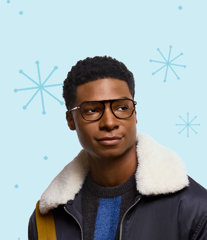 A man with short curly black hair wearing aviator glasses, on a light blue background with a star or snowflake illustrated pattern.