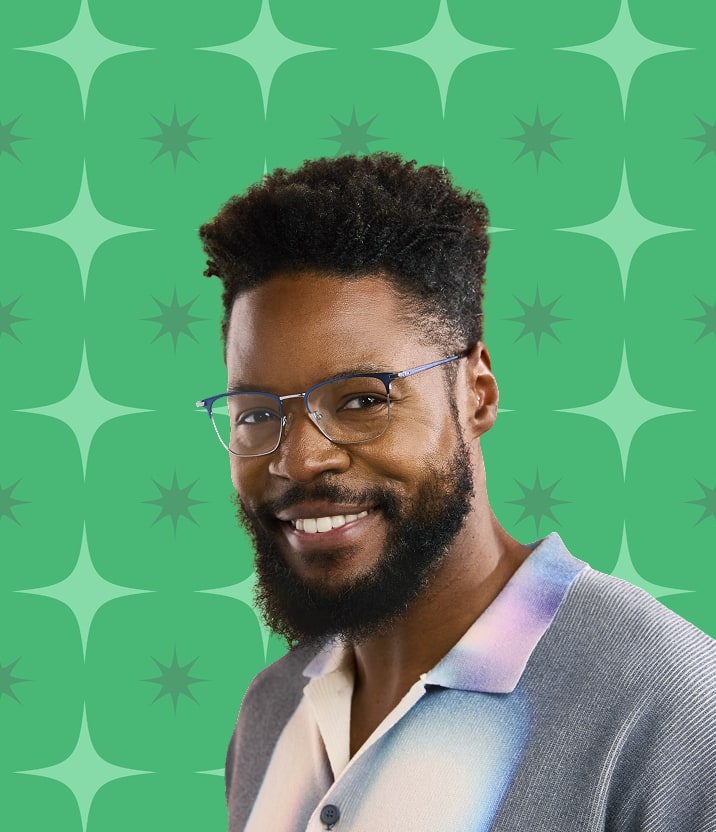 A man with dark brown curly hair and a beard, wearing blue metal square glasses, on a green background with a star motif.