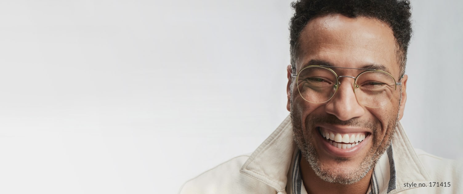 Image of a man wearing Zenni glasses in front of a gray background, with a big smile on his face.