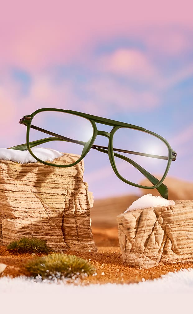 Green full rim plastic aviator glasses in a dessert sunset miniature diorama.