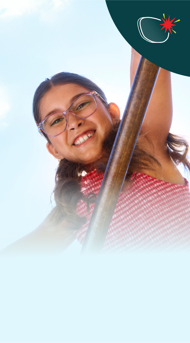 A young girl with glasses smiles while hanging from playground bars, with a bright blue sky in the background. The image highlights durable, impact-resistant lenses for active wearers.