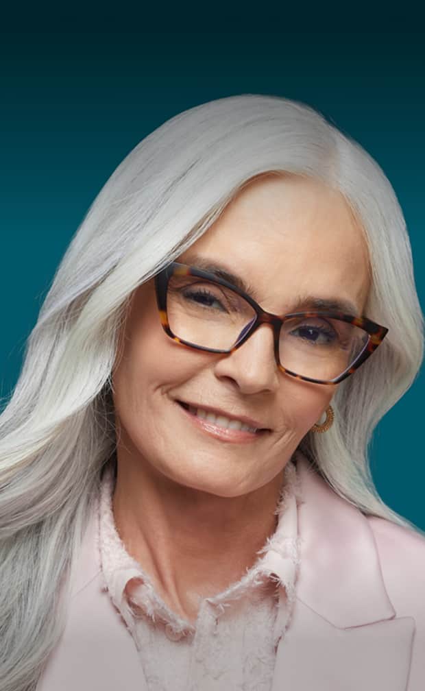 A woman with long white hair wearing cat-eye readers glasses smiles softly at the camera. Text above her reads "Designer Readers" and "Deluxe, starting at $35." A white rectangular button with "Shop now" is displayed at the bottom. The background is a gradient of dark teal and light blue.