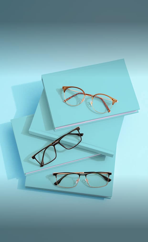 Three pairs of lightweight reading glasses in geometric shapes arranged on a light blue surface. Above, text reads "Lightweight Readers" and "For ultimate comfort." At the bottom, a white rectangular button says "Shop now." The background includes a rolled sheet of blue paper.