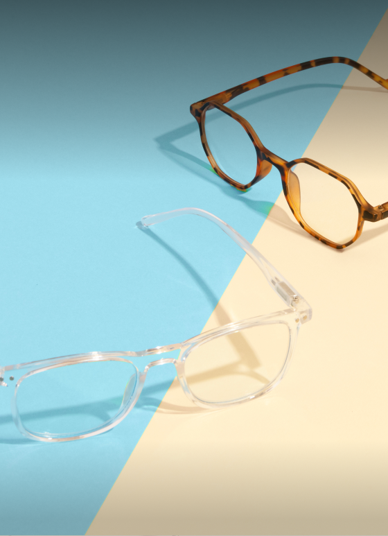 Two pairs of tortoiseshell and clear reading glasses on a colorful background of blue and beige. The text above reads "Over-The-Counter Readers" and "Pairs starting at $6.95." At the bottom, a white rectangular button says "Shop now."