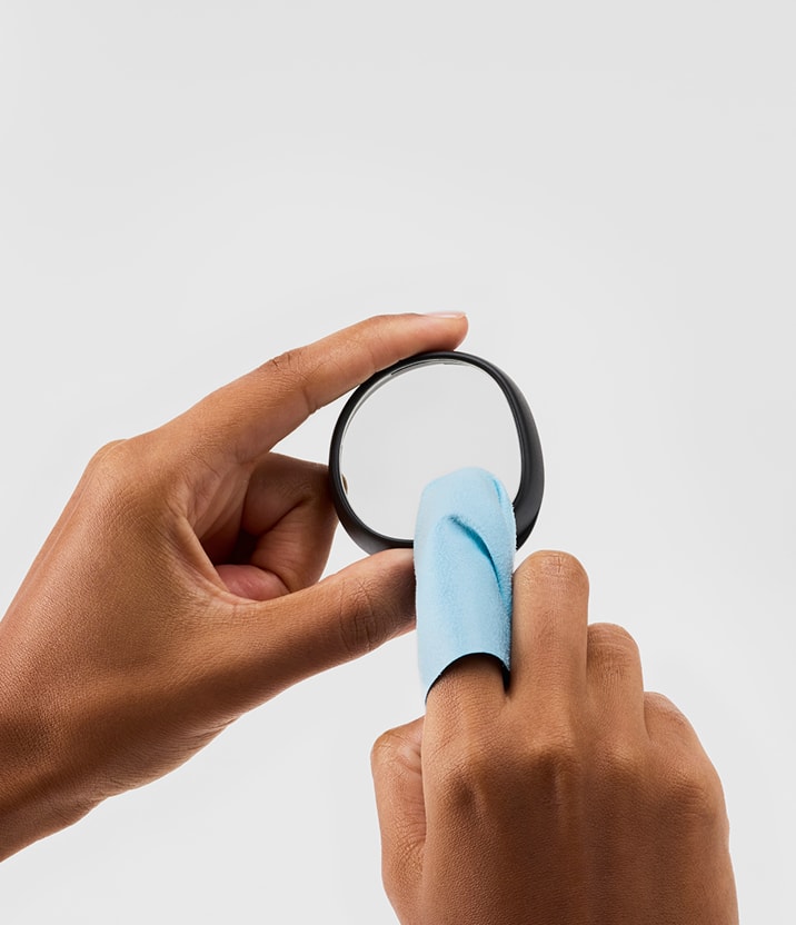 Close-up of hands with a blue lens cloth cleaning a Zenni VR lens insert.