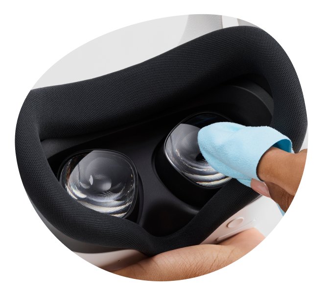 Close-up of a finger cleaning VR lenses inside a Meta Quest headset with a blue microfiber cloth.