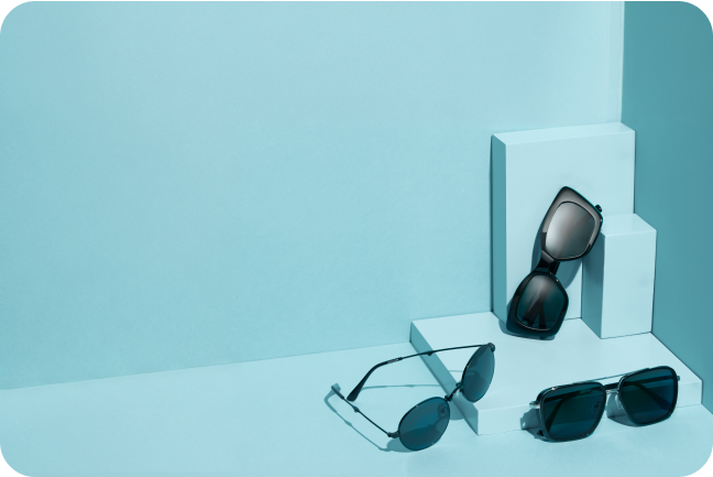 Three pairs of black sunglasses frames on teal blue display blocks..