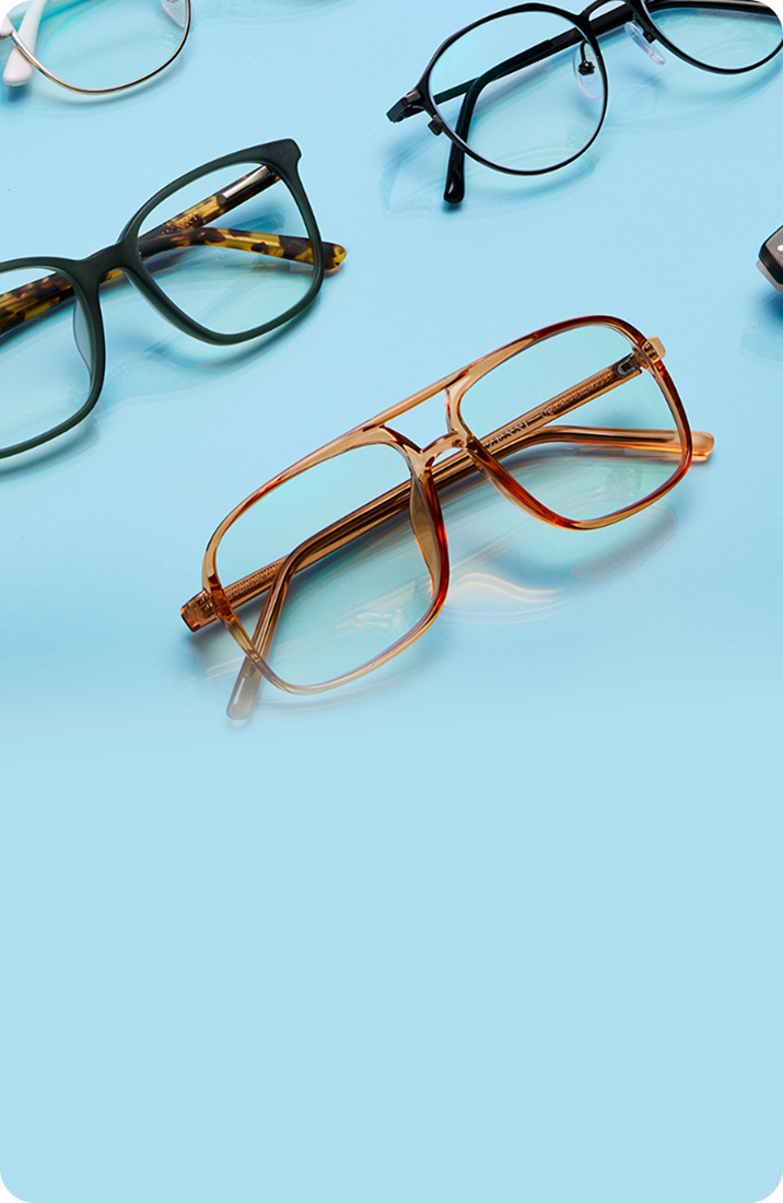 Assortment of stylish eyeglasses in various frame styles and colors arranged on a reflective light blue surface fading to light blue on the left.
